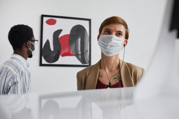 Wall Mural - Low angle portrait of young woman wearing mask in art gallery while looking at sculptures and exploring exhibition, copy space