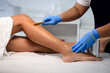 Cosmetologist beautician waxing female legs in the spa center beauty salon cosmetology concept