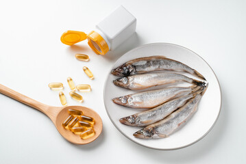 Wall Mural - Omega 3 pills on spoon, fish oil and fish on white background. 
Health and immunity strengthening fish oil capsules. 
Healthy food