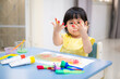 the toddler is happy with the painted colorful hands. baby girl smile with painted colorful hand.