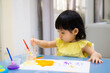 child painting with a paintbrush on the table. toddler draw watercolor.