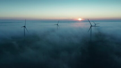 wind turbine at sunrise in heavy fog. wind farm generating green energy