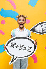 excited schoolchild holding speech bubble with math formula illustration near paper elements and pencil on yellow