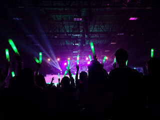 Crowd at concert : Silhouette people crowd happy and cheering with led foam stick light in front of bright colorful stage lights