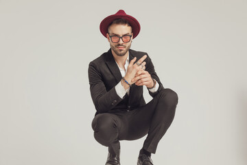 Wall Mural - Positive fashion model adjusting his rings and smiling, wearing hat