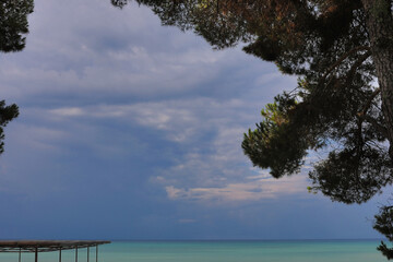 Natural background of blue sky with clouds at sunset and azure sea water. Copy space.