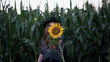 Beautiful young woman in a field of sunflowers in a hat. and covering face with sunflower