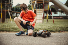 Teen Boy With Electric Remote Control Car Toy Play Outdoor On Sidewalk And Have Fun While Enjoy His Childhood