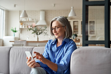 relaxed mature old 60s woman, older middle aged female customer holding smartphone using mobile app,