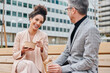 © IVAN GENER/Stocksy - Smiling businesspeople eating lunch on a bench