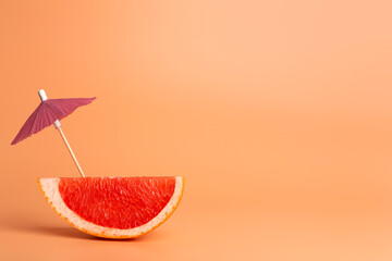 Wall Mural - Grapefruit slice on a orange background. Summer, vacation and travel minimal concept.