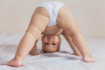 beautiful baby in white panties standing on his head