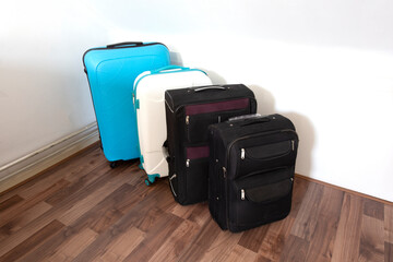 Various suitcases or travel bags in a row near white wall, modern luggage bags for tourism