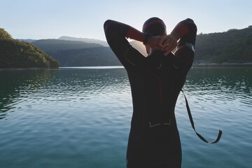 triathlon athlete starting swimming training on lake