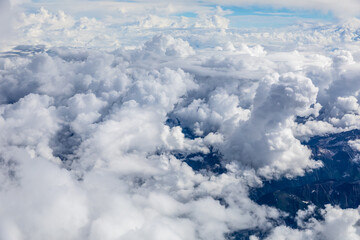 Aerial view above the clouds and mountain peaks on a sunny day.