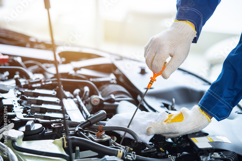 Close up hand auto mechanic check new car engine oil in car service center.