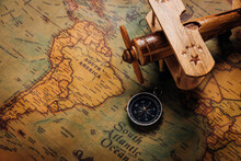 Old Compass Discovery And Wooden Plane On Vintage Paper Antique World Map Background, Retro Style Cartography Travel Geography Navigation, Columbus Day Concept