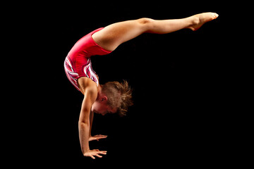 Wall Mural - Young female gymnast on a black background