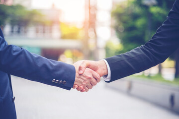 Team Business Partners shaking hands together to Greeting Start up new project. Shakehand Teamwork Partnership outside office modern city background. Businessman handshake together.  Business concept