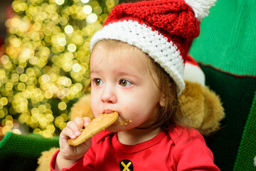 Wall Mural - Little cute baby on the christmas tree tasting christmas sweet treats. Close up kids face.