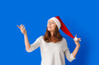 © Pixel-Shot - Beautiful young woman in Santa hat on color background