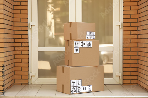 Cardboard boxes with different packaging symbols on floor near entrance. Parcel delivery