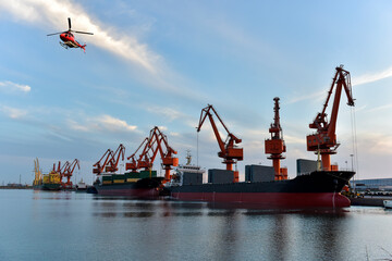 in the sunset, the crane is lifting goods from the wharf to the transport ship. and there are planes