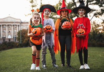 Sticker - Cute little kids with pumpkin candy buckets wearing Halloween costumes in park