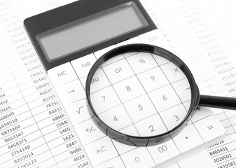 Magnifying glass with calculator on financial and accounting data.