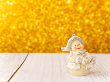 Christmas Toy In The Shape Of A Snowman On A Gold Background.