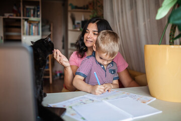 Wall Mural - Distant education. Mother doing online homework with her little son at home, family lifestyle