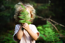 Unrecognizable Small Child Outdoors In Summer Nature, Hiding Against Fern Leaf.