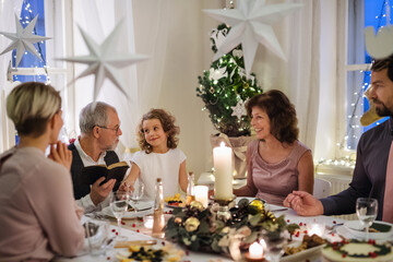 Small girl with parents and grandparents indoors celebrating Christmas.