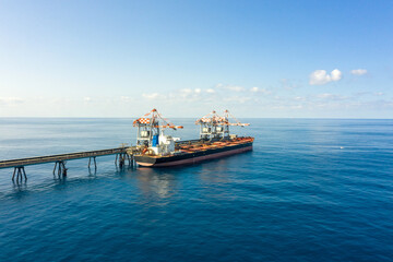 Coal carrier Cargo Ship docked at a commercial pier during unloading operation, Aerial view.
