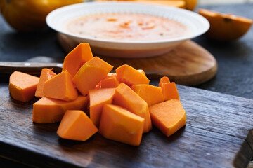 Cut pieces of raw pumpkin on wooden board on table