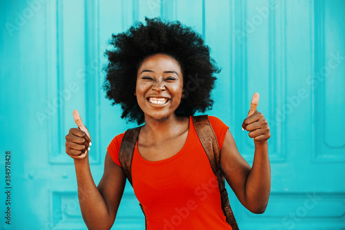 Young smiling gorgeous african woman with short curly hair standing outdoors and showing thumbs up. Diversity concept.