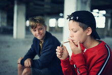Group Of Teenagers Boys Indoors In Abandoned Building, Smoking Cigarettes.