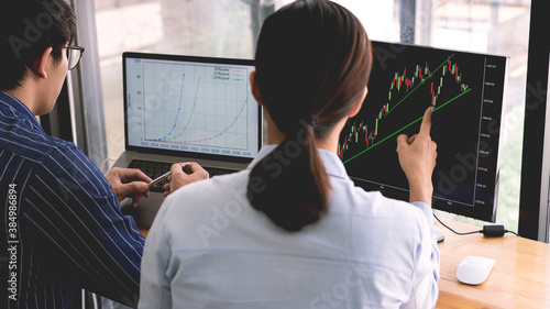 broker showing some ascending to his colleague planning and analyzing graph stock market trading with stock chart data on multiple computer screens.