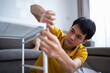 © Garun Studios - Asian men assembling furniture in the living room at home.