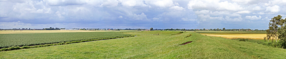 extremely flat polder landscape with a dike, in the netherlands