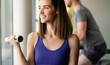 © NDABCREATIVITY - Beautiful woman doing exercises with dumbbell in gym. Girl is enjoying with her training process