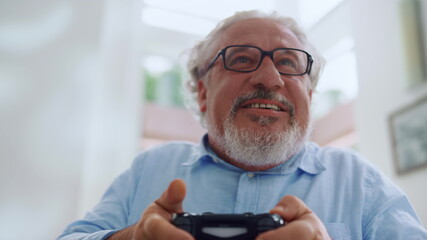 Senior man playing video game. Older man using gamepad for computer game