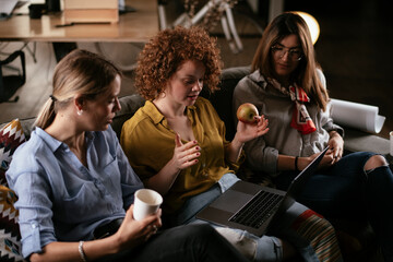 Wall Mural - Girlfriends talking and laughing in office. Beautiful women drinking coffee in the office.