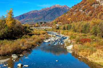 Wall Mural - Small alpine river and colorful autumnal mountains in Switzerland.