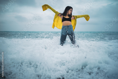 Fotomural ragazza con maglia gialla e jeans si fa il bagno a mare in inverno