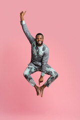 Wall Mural - Excited black man jumping up over pink background