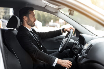 Handsome businessman driving car to airport, going on business trip