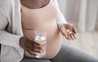 © Prostock-studio - Prenatal Vitamins And Supplements. Unrecognizable black pregnant woman taking pills and water