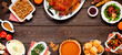 Classic Thanksgiving turkey dinner. Top view frame on a dark wood banner background with copy space. Turkey, mashed potatoes, dressing, pumpkin pie and sides.