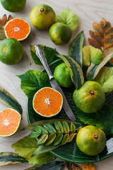 Lots of tangerines and autumn leaves on a light table. Background image. Place for text. Flat lay.